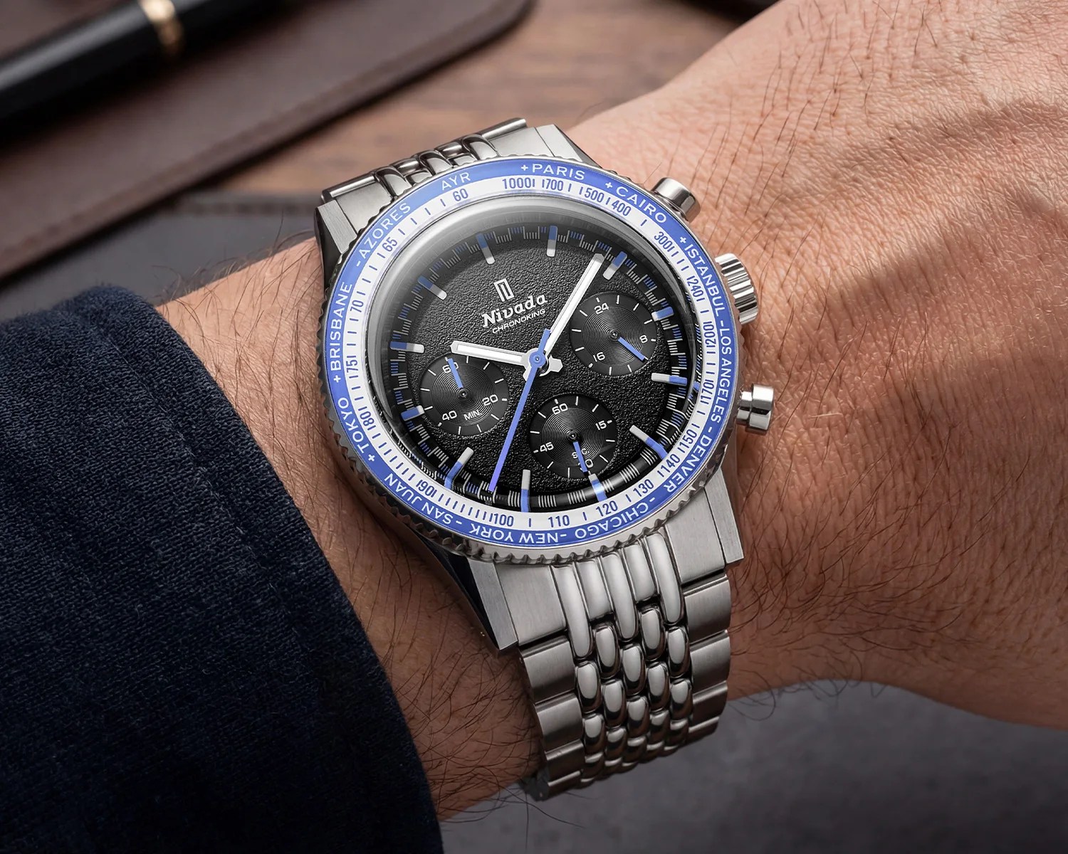 Stainless steel Nivada chronoking wristwatch with black textured dial and blue accents on a wrist.
