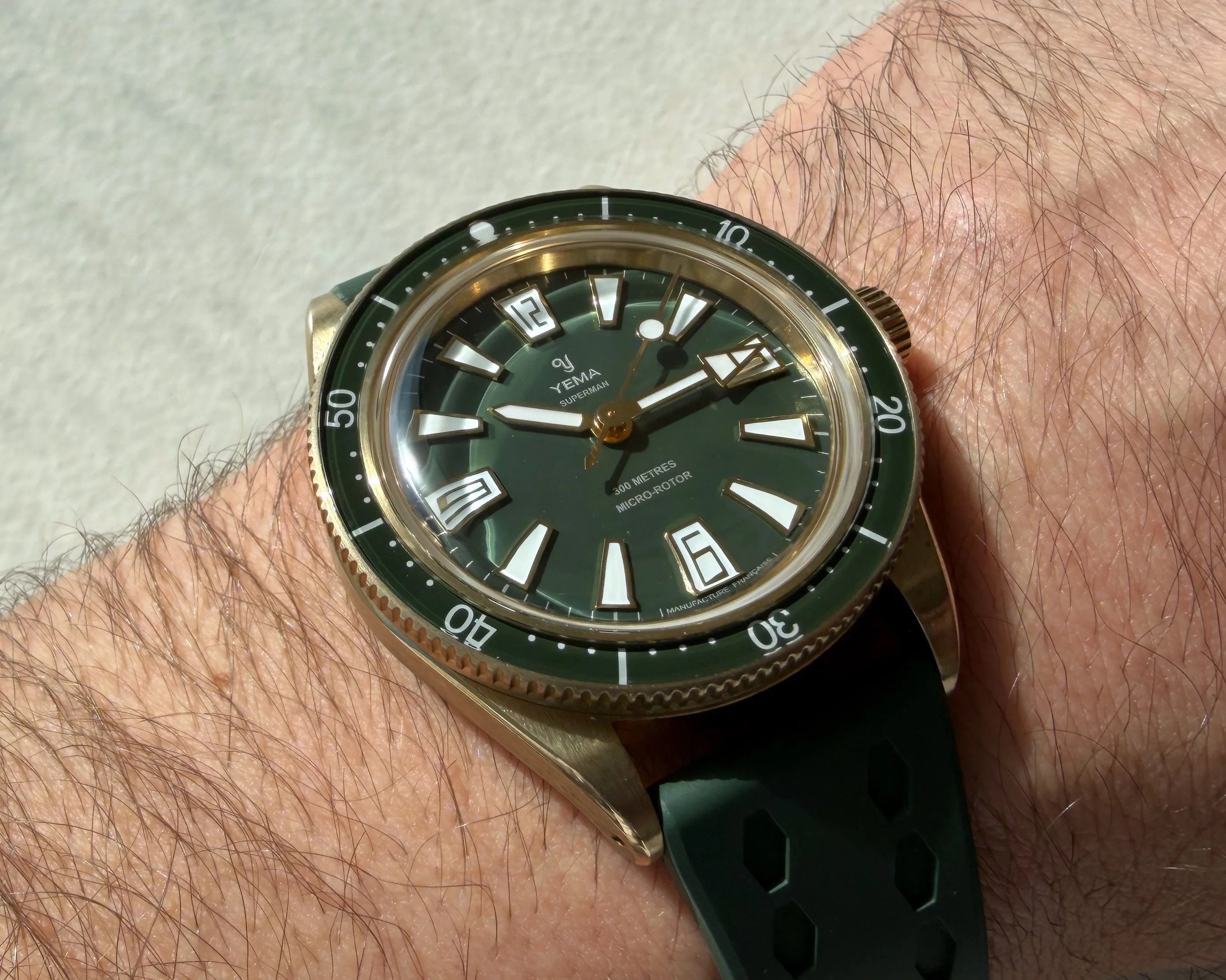 Green dial Yema Superman wristwatch with bronze case and green rubber strap worn on a wrist.