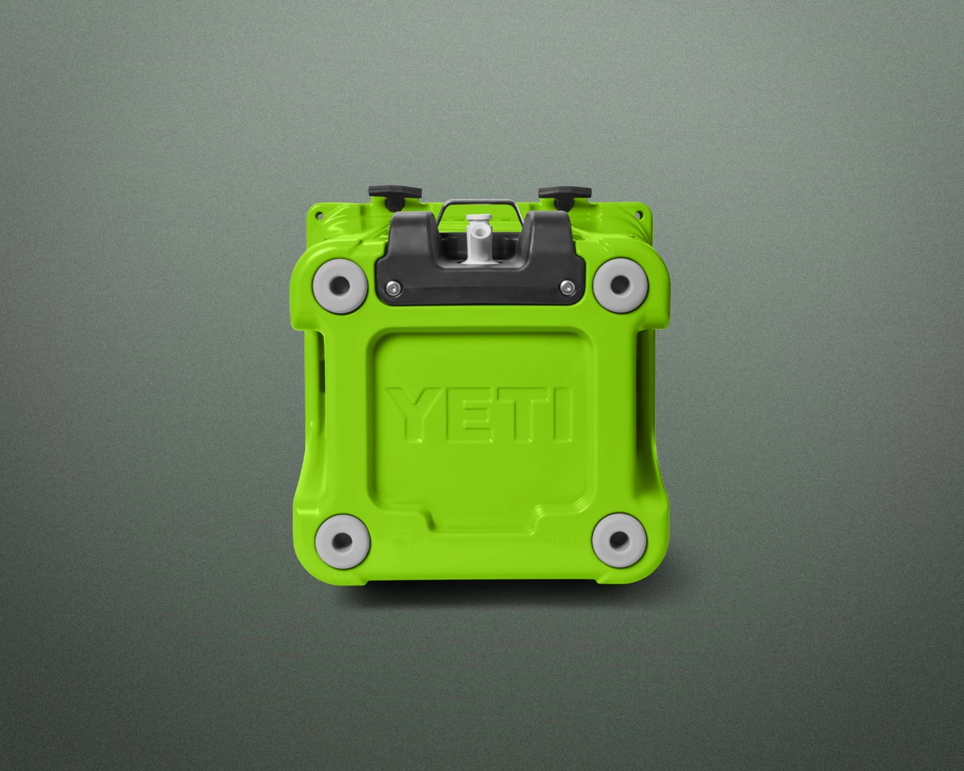 Bright green YETI cooler viewed from the bottom showing four white rubber feet and black latch hardware.