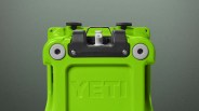 Bright green YETI cooler lid with black latch and white drain plug on a gray background.