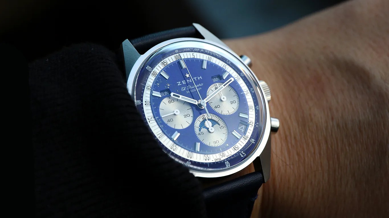 Silver Zenith El Primero chronograph watch with blue dial and blue leather strap on a wrist.