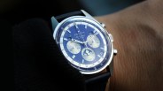 Silver Zenith El Primero chronograph watch with blue dial and blue leather strap on a wrist.