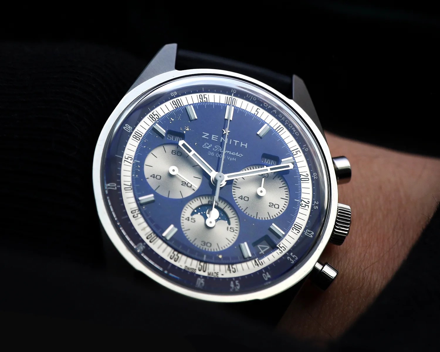 Close-up of a Zenith El Primero wristwatch with a blue dial, three subdials, and a blue strap worn on a wrist.