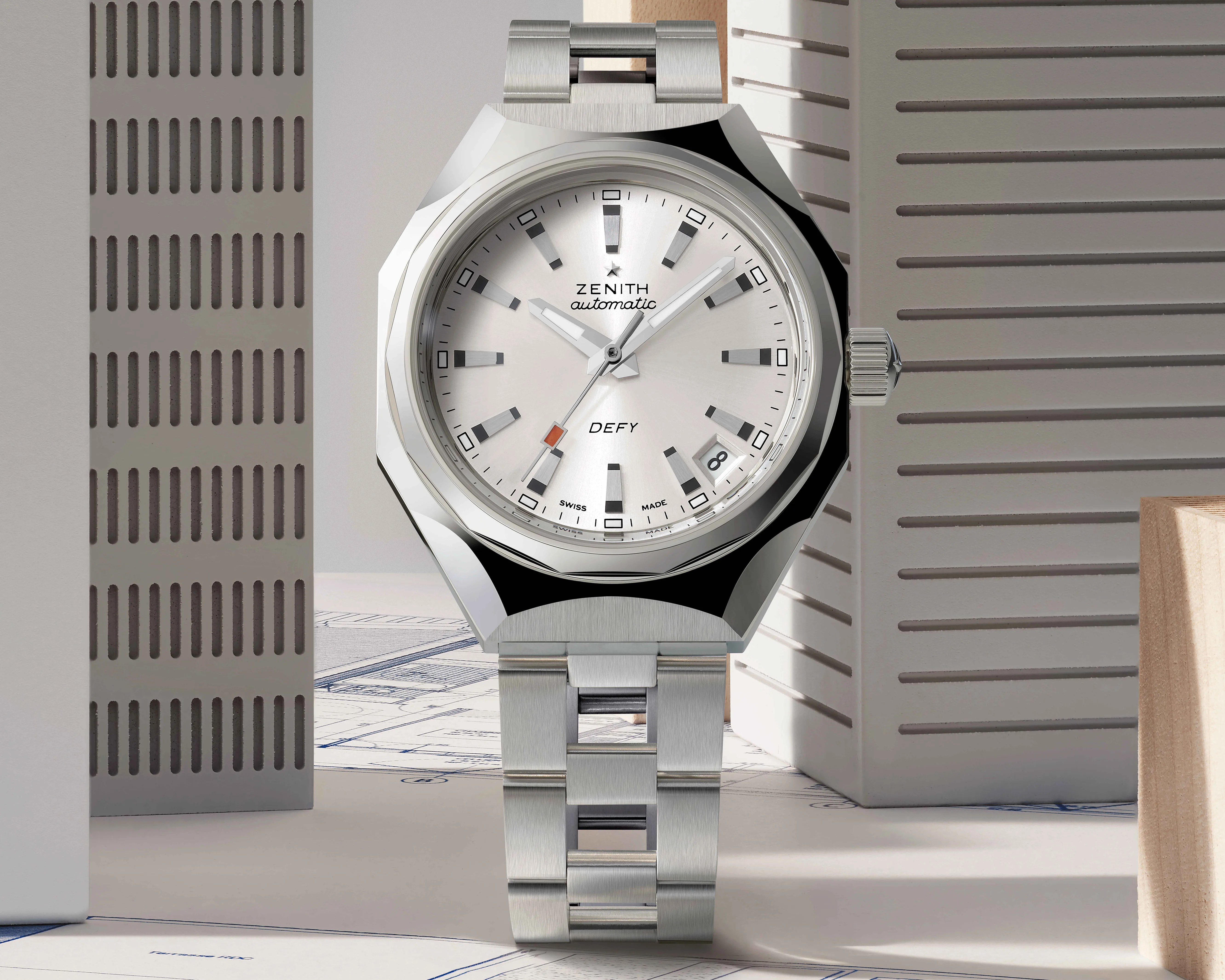 Silver Zenith Defy automatic wristwatch with a brushed metal bracelet and a date window at 4 o'clock.