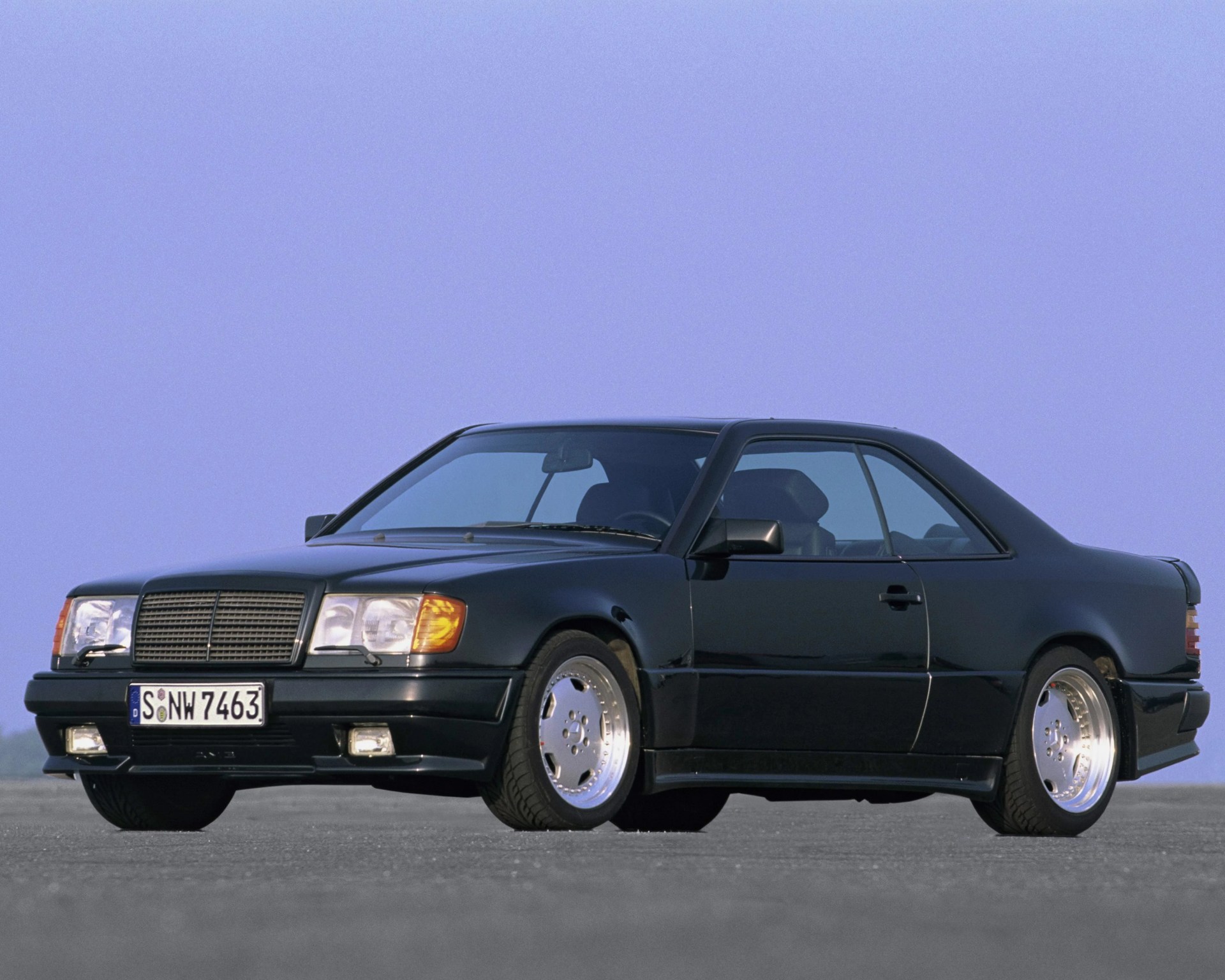Black two-door Mercedes-Benz coupe with polished deep-dish wheels on a flat surface.