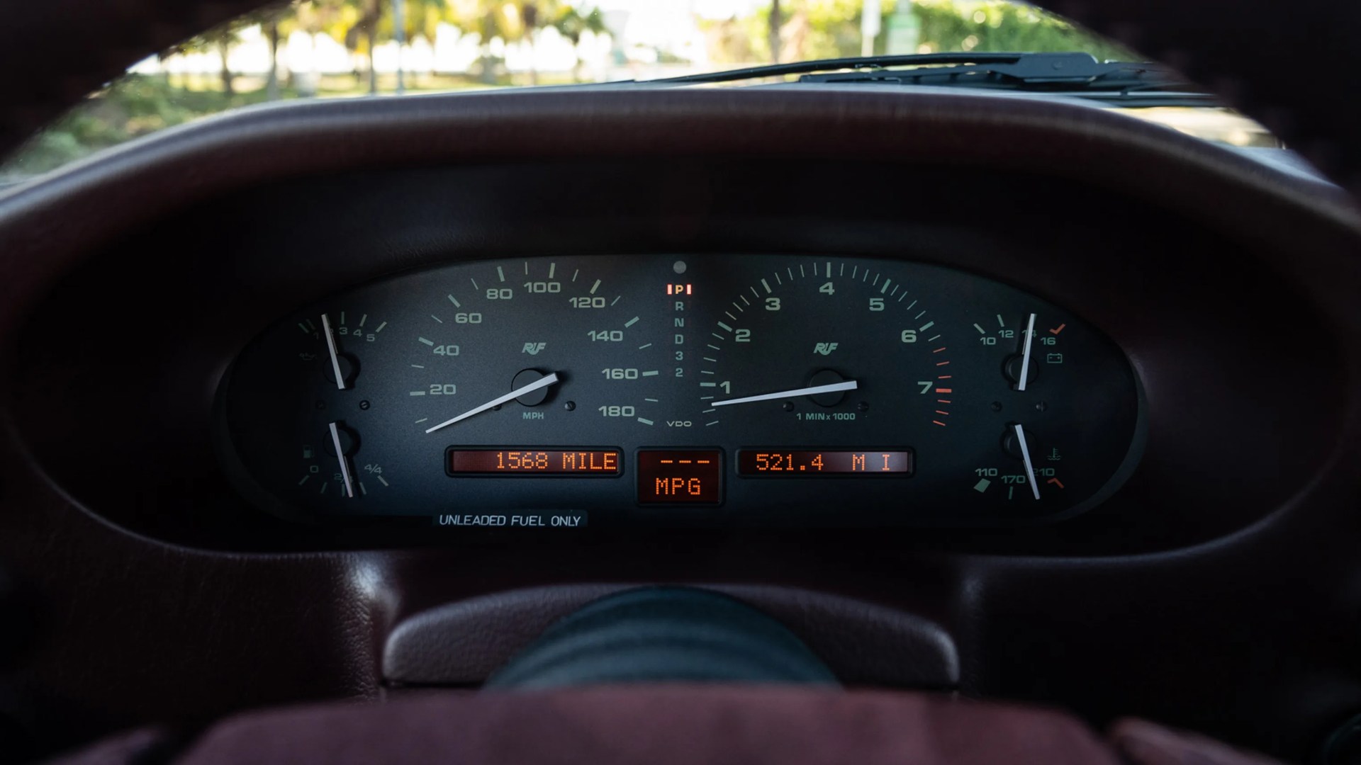 Car dashboard with speedometer, tachometer, fuel gauge, temperature gauge, and digital odometer reading 1568 miles.