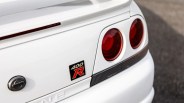 Close-up of white Nissan Skyline 400R rear with round red taillights and emblem badge.