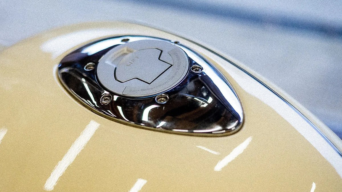 Close-up of a beige motorcycle fuel tank with a chrome and silver fuel cap.