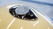 Close-up of a beige motorcycle fuel tank with a chrome and silver fuel cap.
