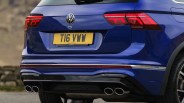 Rear view of a blue Volkswagen car with dual exhaust pipes and illuminated taillights.