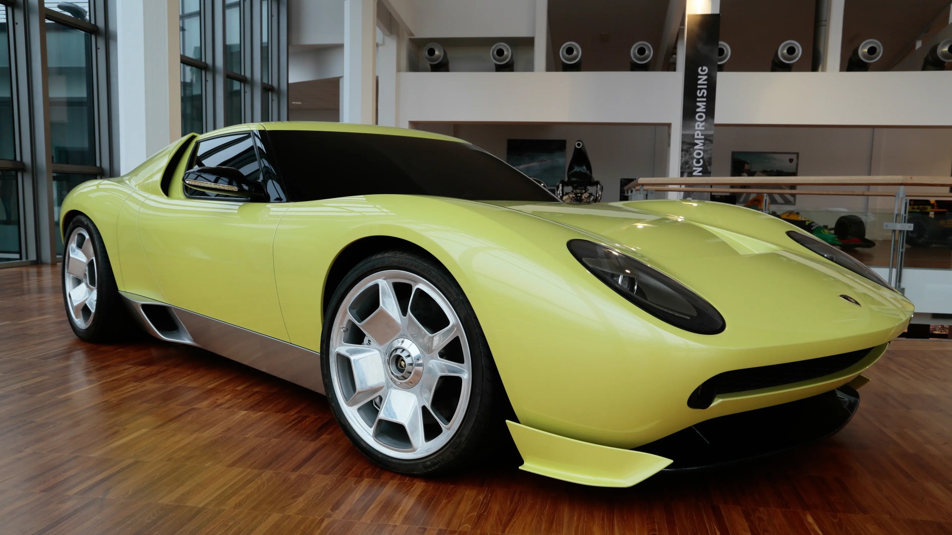 Lime green Lamborghini Miura concept car with silver wheels on a wooden floor indoors.