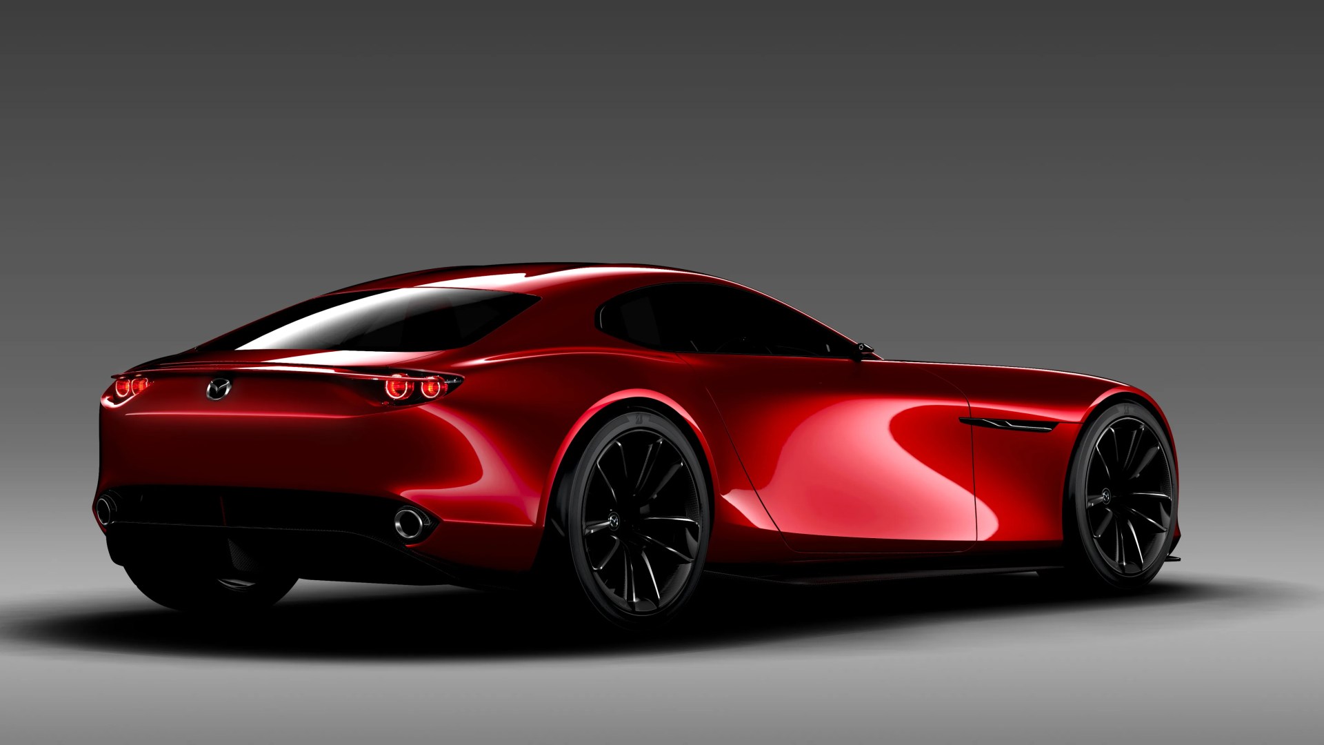 Shiny red Mazda sports car with black wheels shown from rear side on gray background.