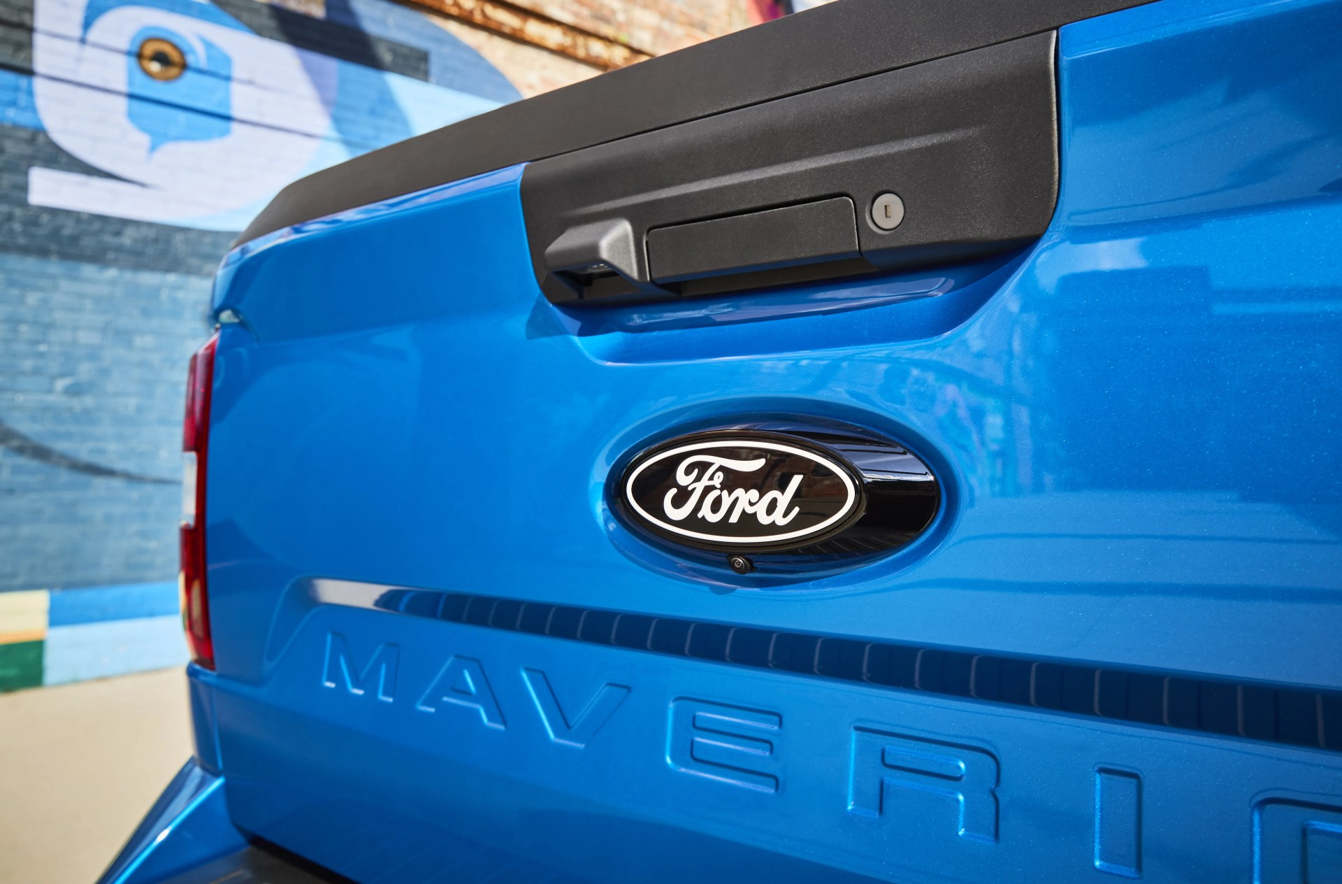 Close-up of blue Ford Maverick truck tailgate with black handle and Ford emblem.