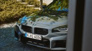 Front view of a gray BMW M2 with a German license plate parked on a cobblestone surface.