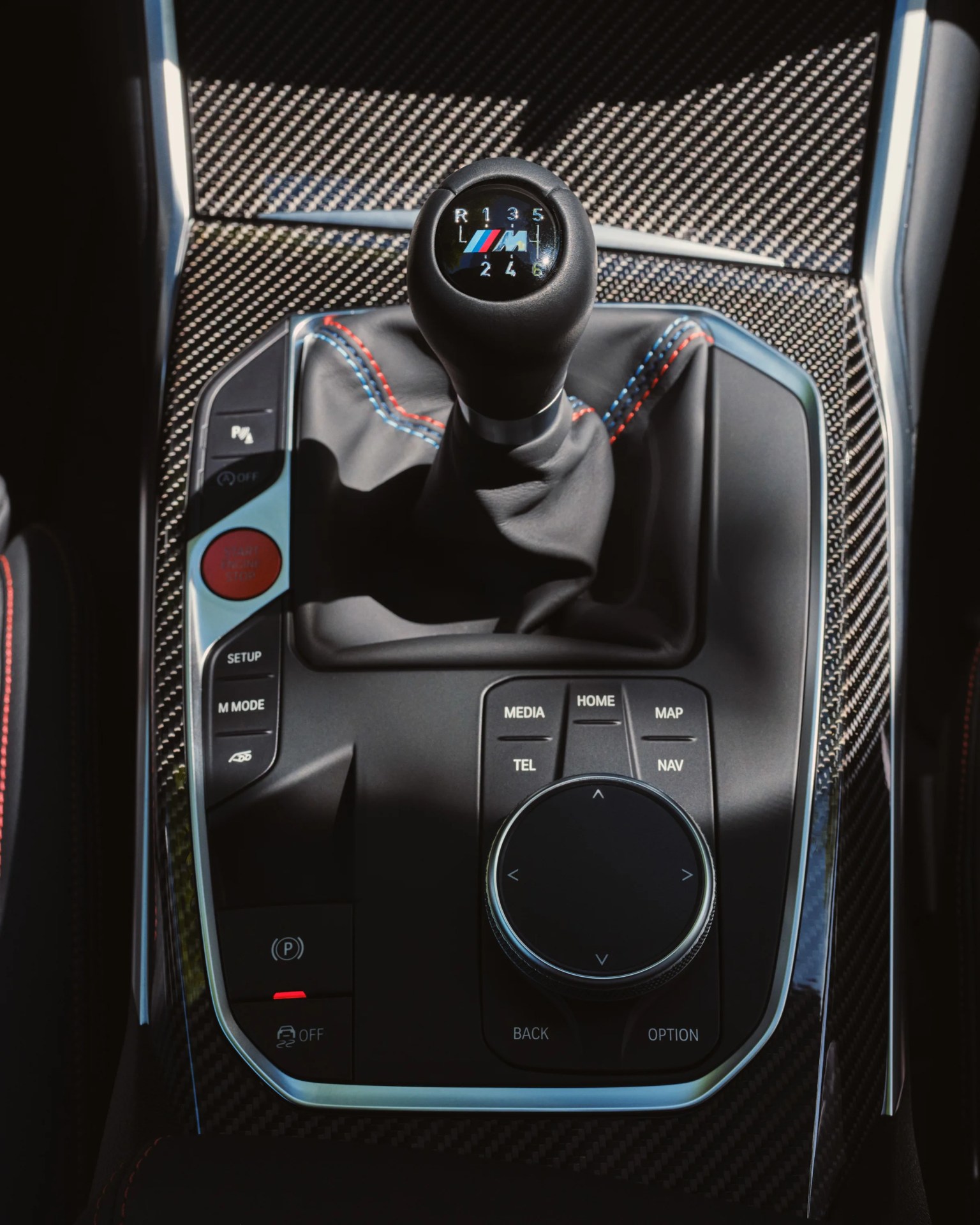 BMW M series manual gear shift knob with carbon fiber center console and control buttons.