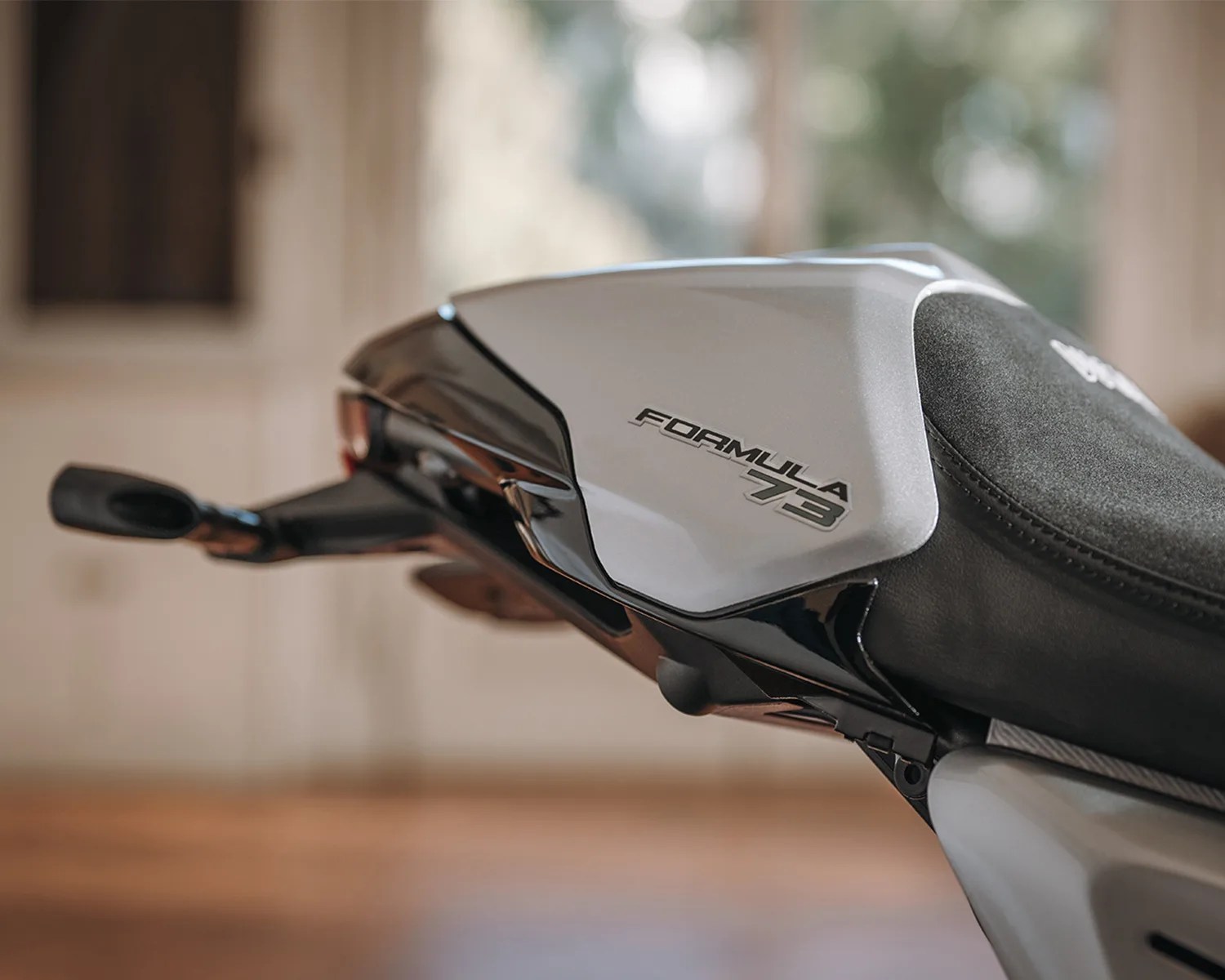 Close-up of a silver and black motorcycle tail section with "Formula 73" text on the side.