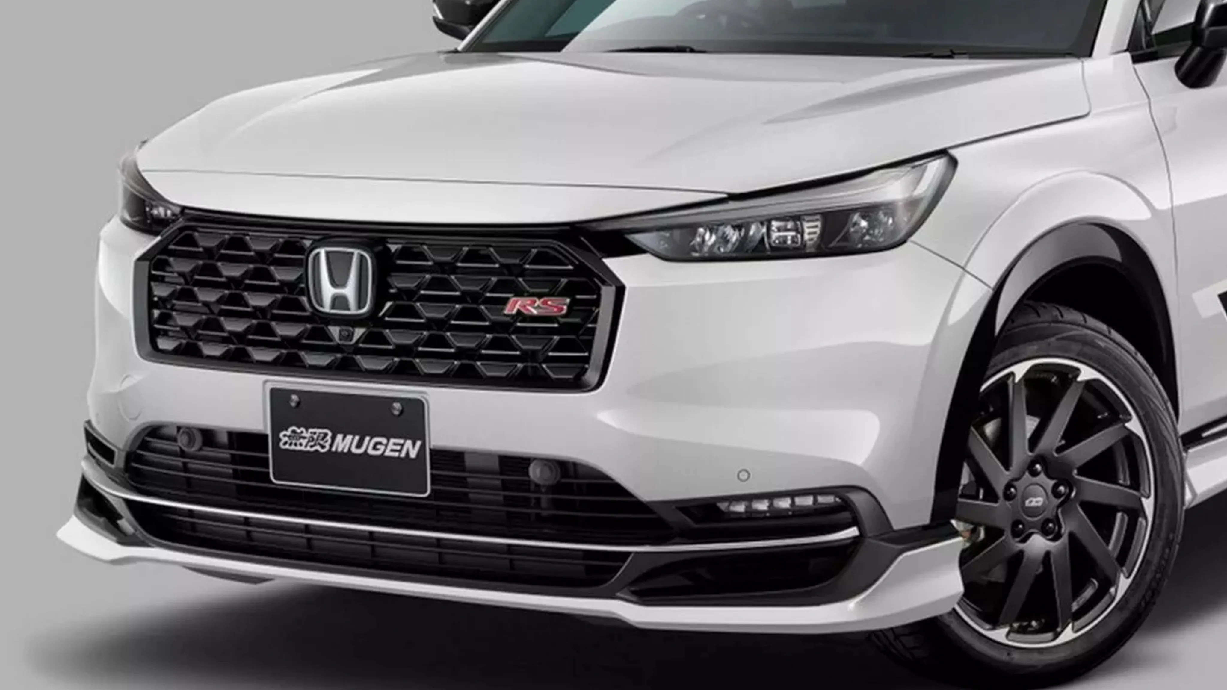 Front view of a white Honda car with black honeycomb grille, RS badge, Mugen license plate, and black alloy wheels.