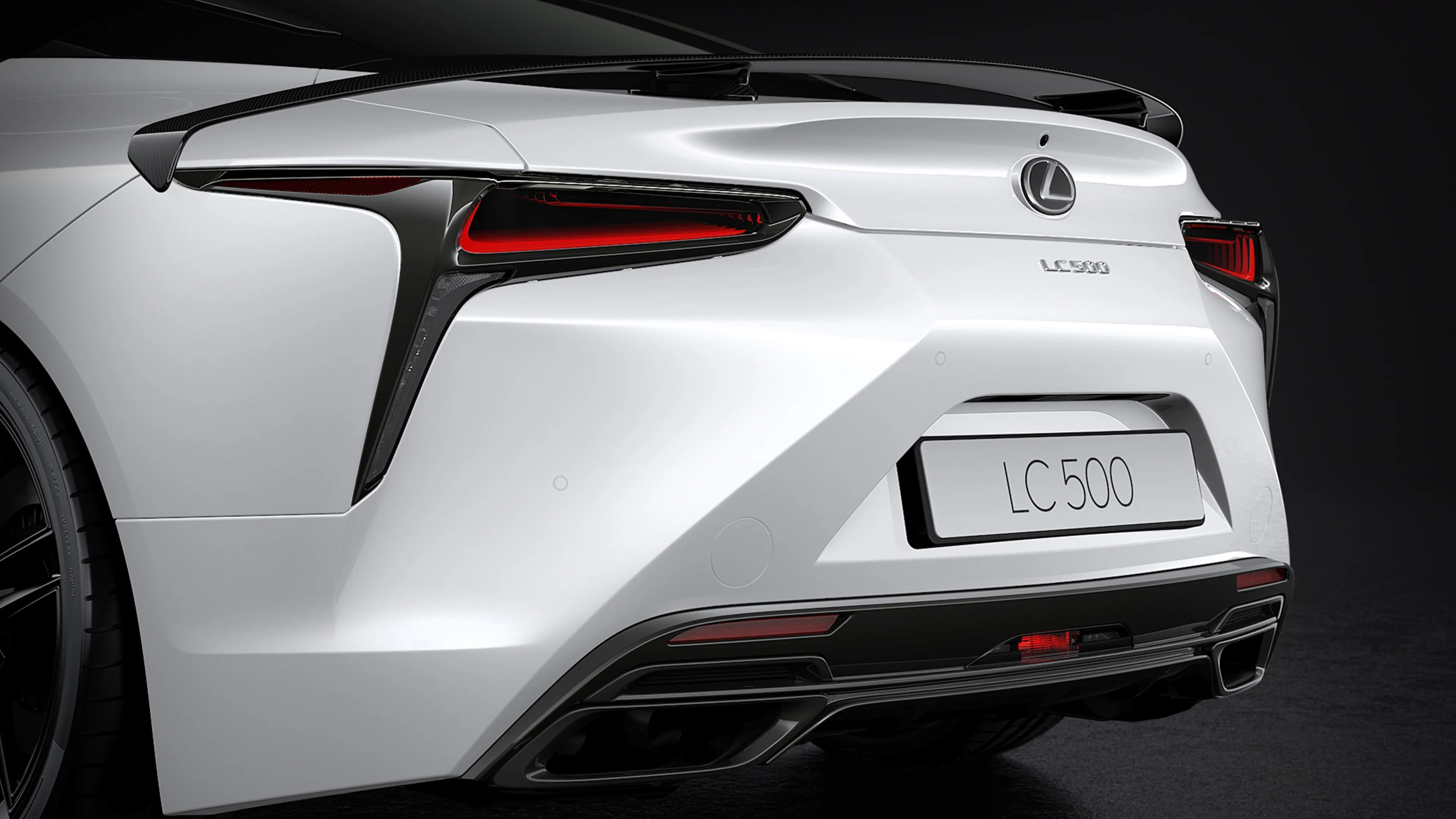 Rear view of a white Lexus LC 500 with black accents and red taillights on a dark background.