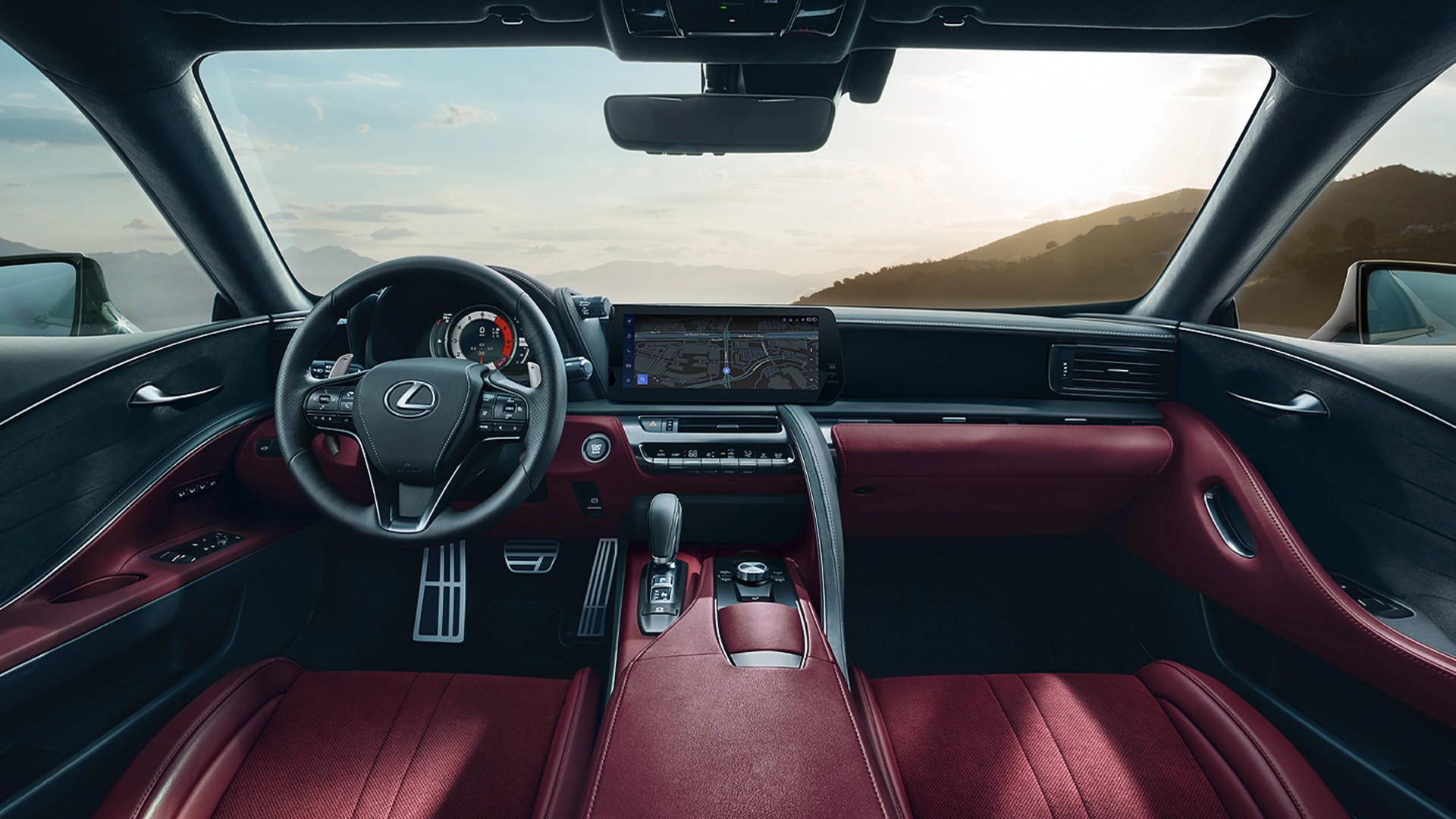 Lexus car interior with black steering wheel, digital dashboard, and red leather seats and trim.