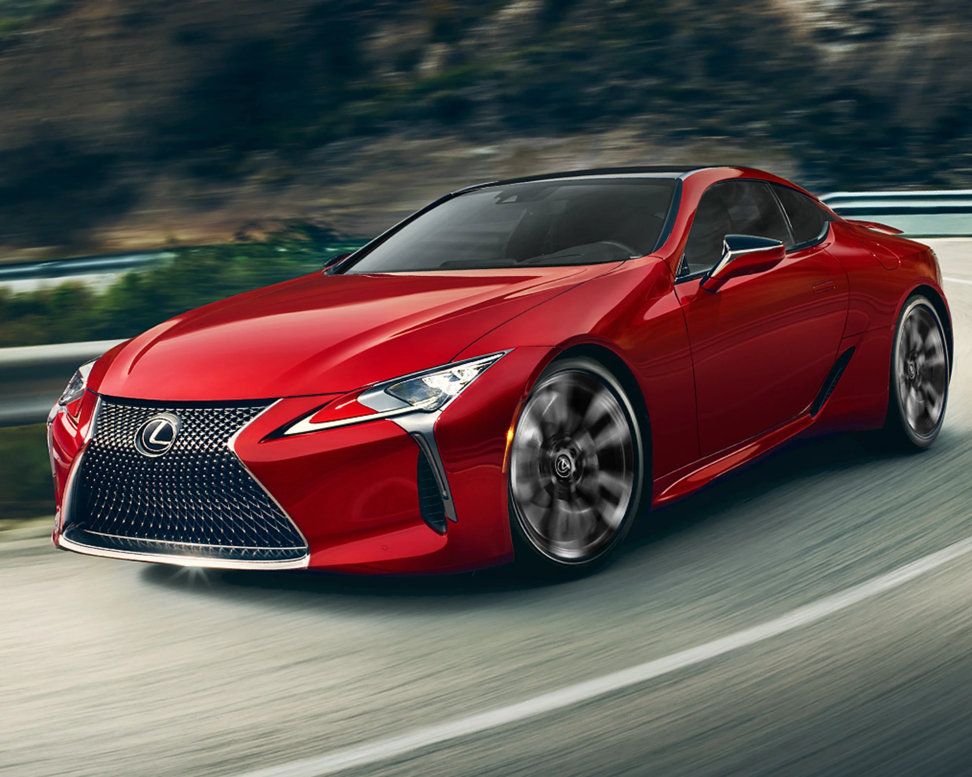 Red Lexus sports car with black roof and spinning wheels driving on a curved road.