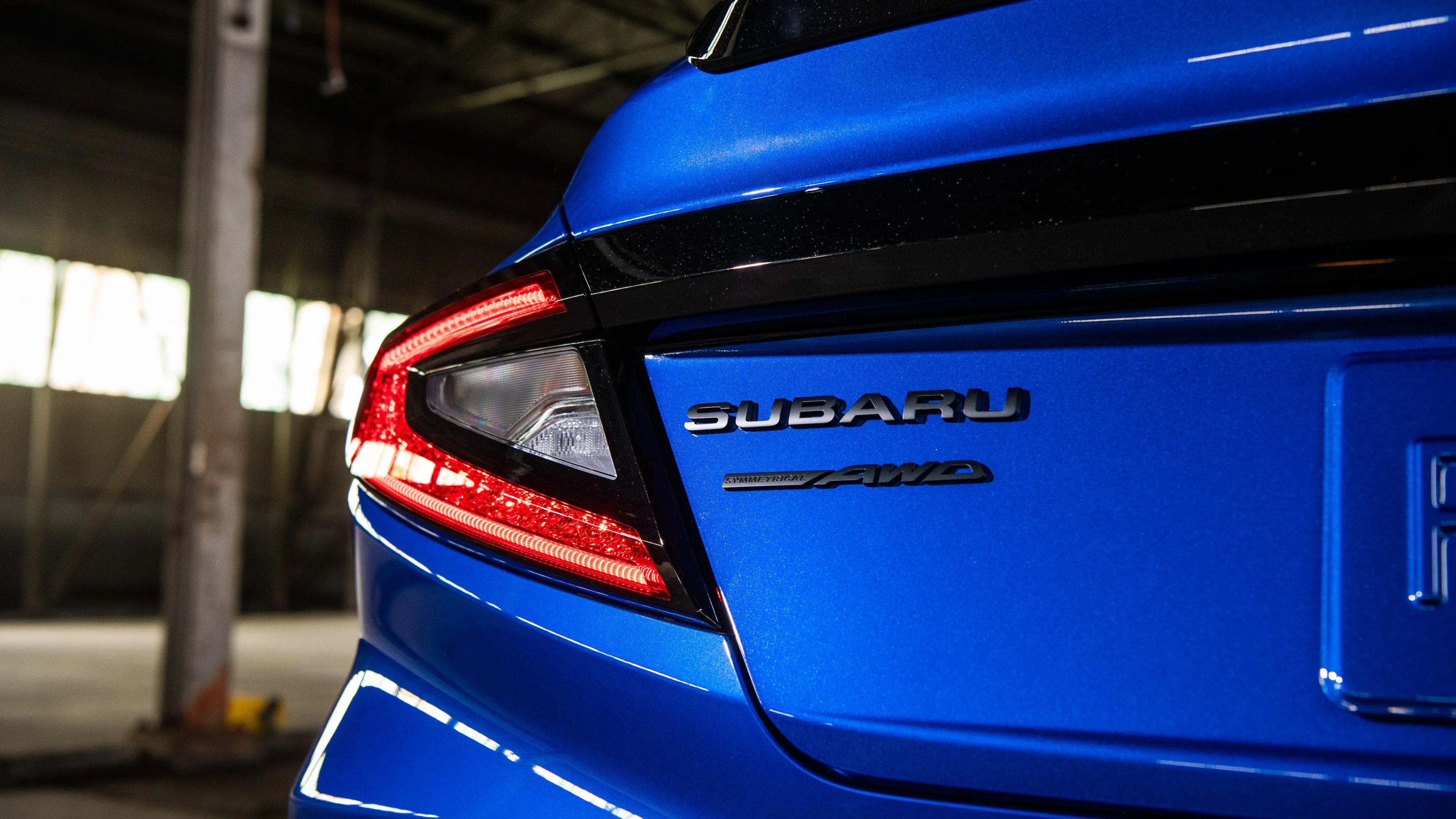Rear close-up of a blue Subaru car showing the taillight and "SUBARU AWD" badge.