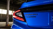Rear close-up of a blue Subaru car showing the taillight and "SUBARU AWD" badge.