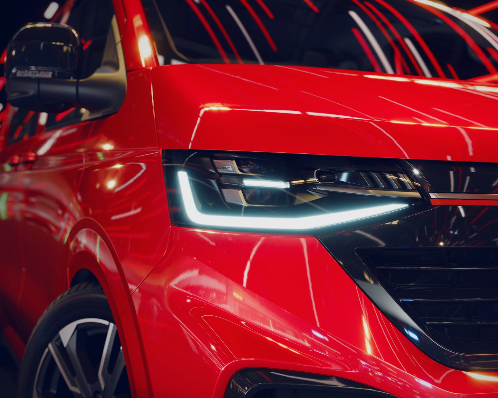 Close-up of a red car's front left side showing a modern LED headlight and part of the wheel.