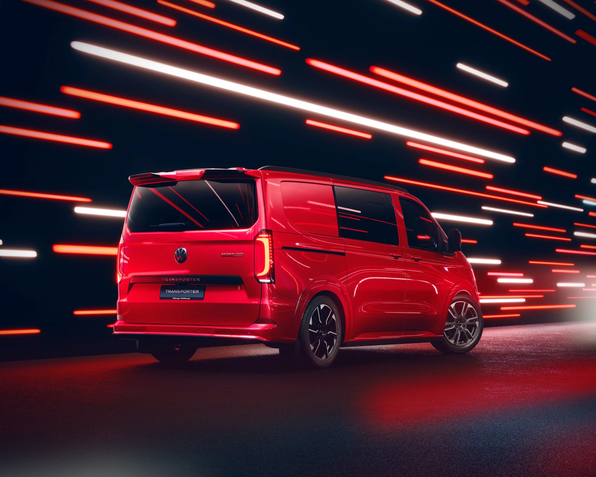 Red Volkswagen Transporter van with black-tinted windows and sporty alloy wheels against a dark background with red and white light streaks.