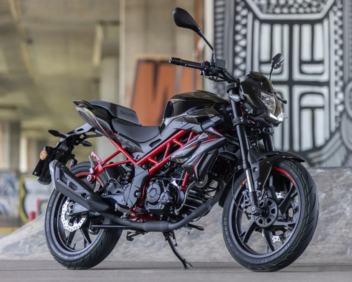 Black and red Benelli motorcycle with exposed frame and disc brakes parked indoors.