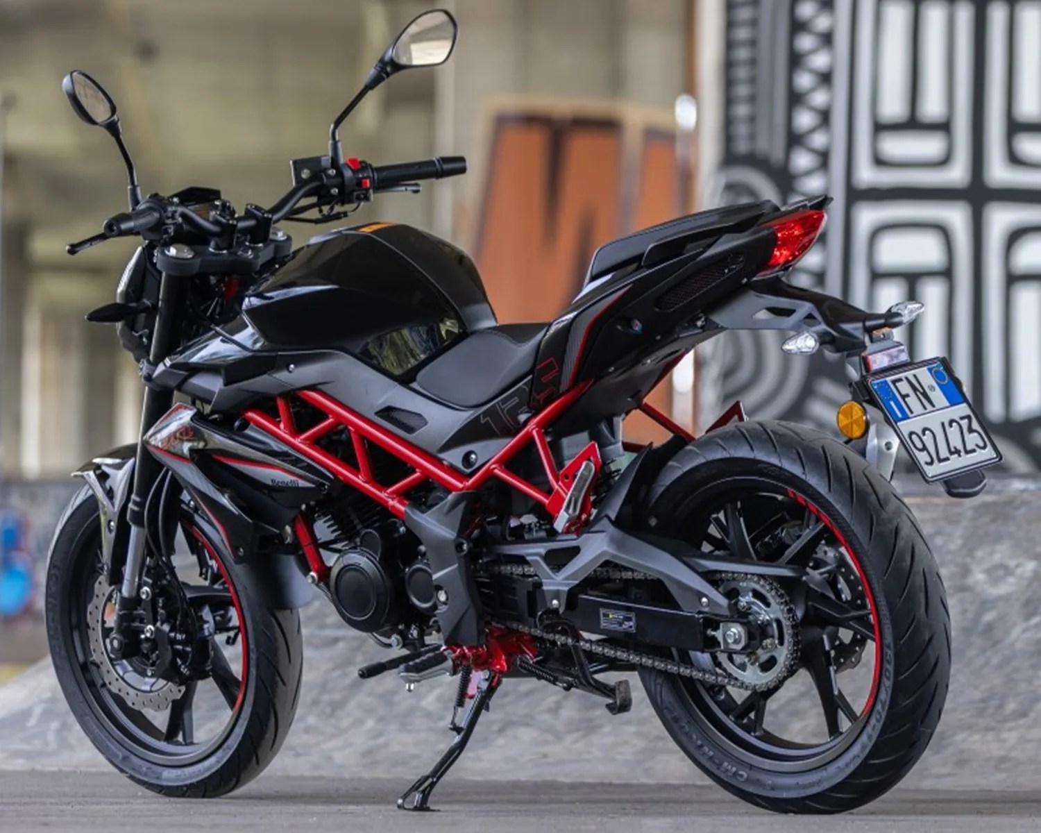 Black and red sport motorcycle with exposed red frame and rear license plate in an urban setting.
