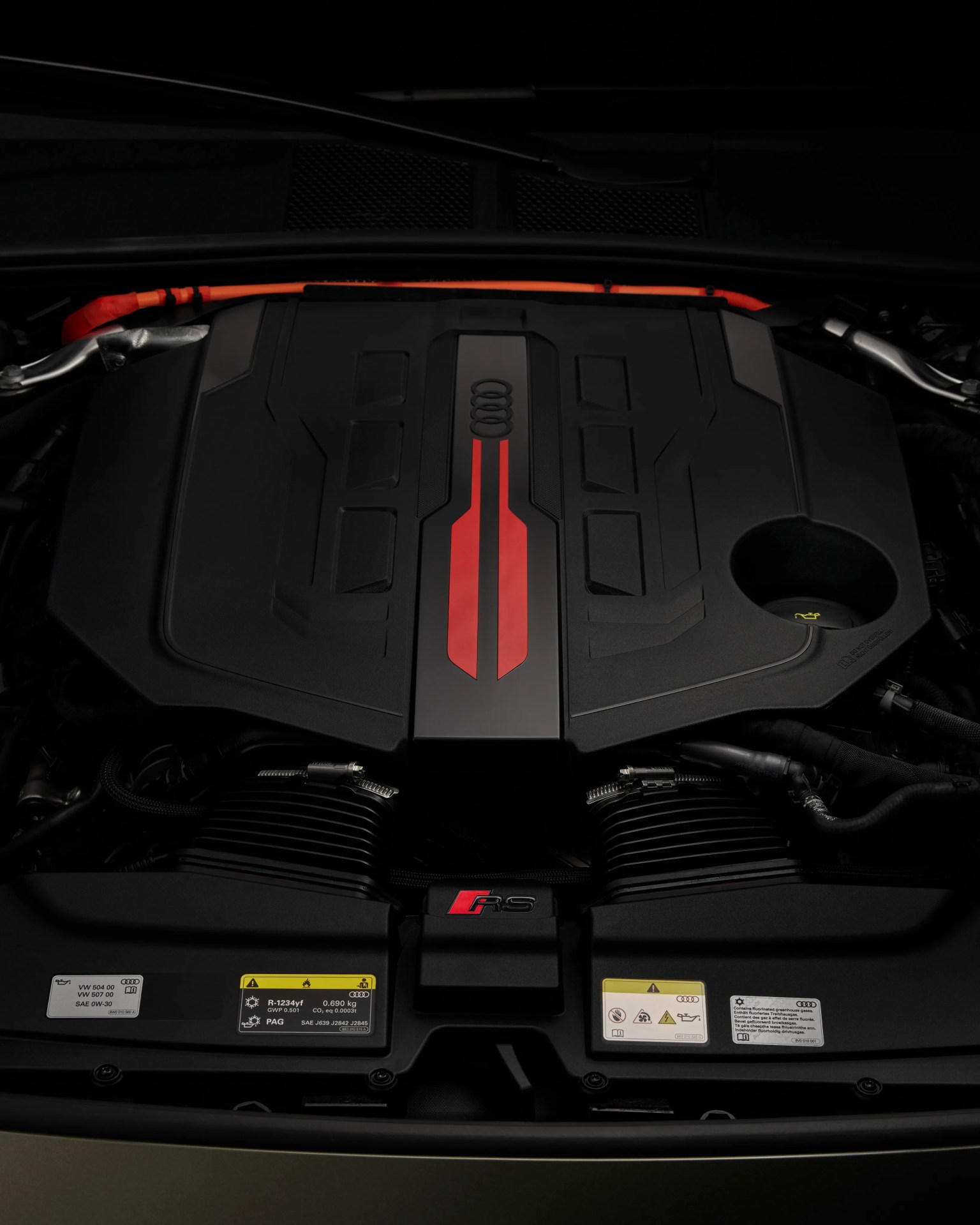 Audi RS engine with black cover featuring red accents and orange high-voltage cable.