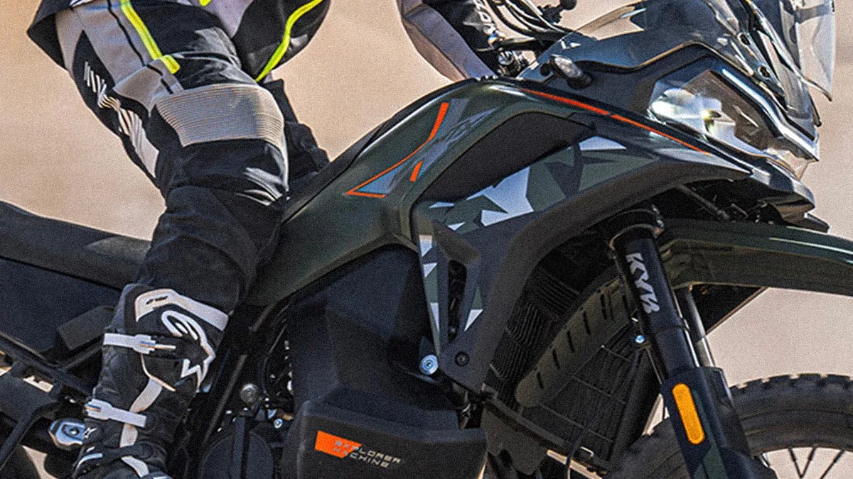 Close-up of a black and dark green motorcycle with orange accents and a rider wearing black and gray gear.