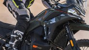 Close-up of a black and dark green motorcycle with orange accents and a rider wearing black and gray gear.