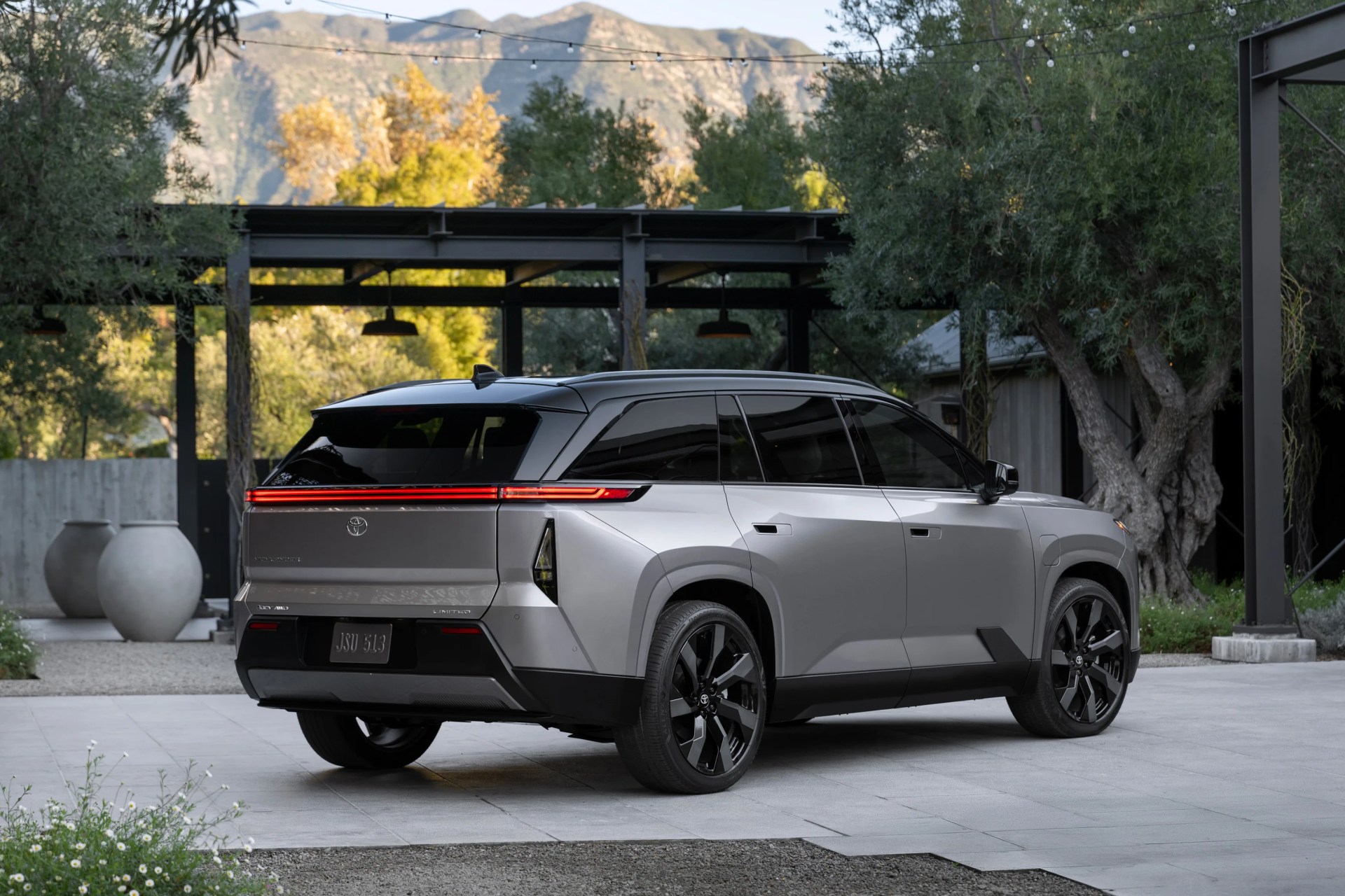 Silver Toyota SUV with black roof and tinted windows parked on a tiled driveway near trees and large vases.