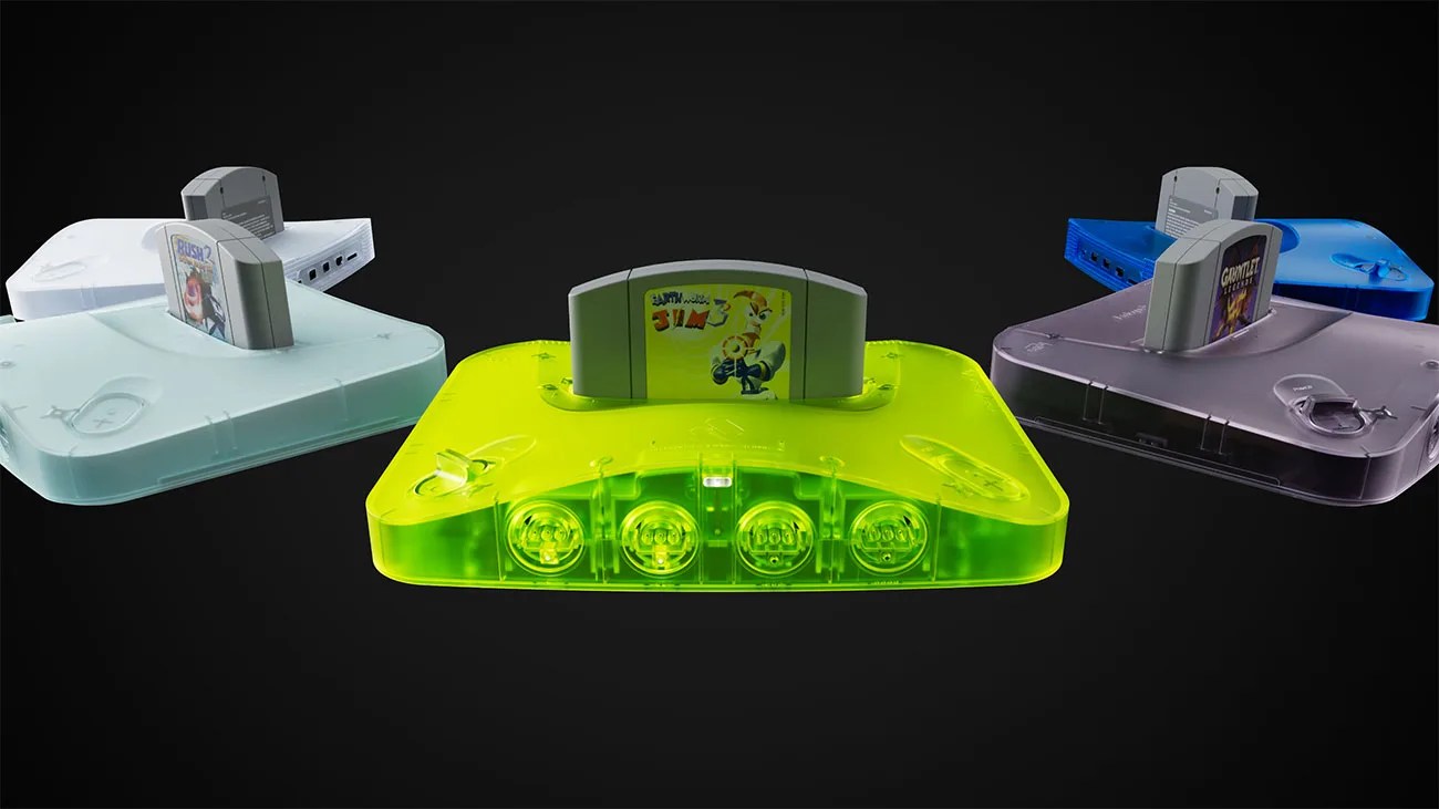 Four translucent Nintendo 64 consoles in green, blue, purple, and white, each with a game cartridge inserted.