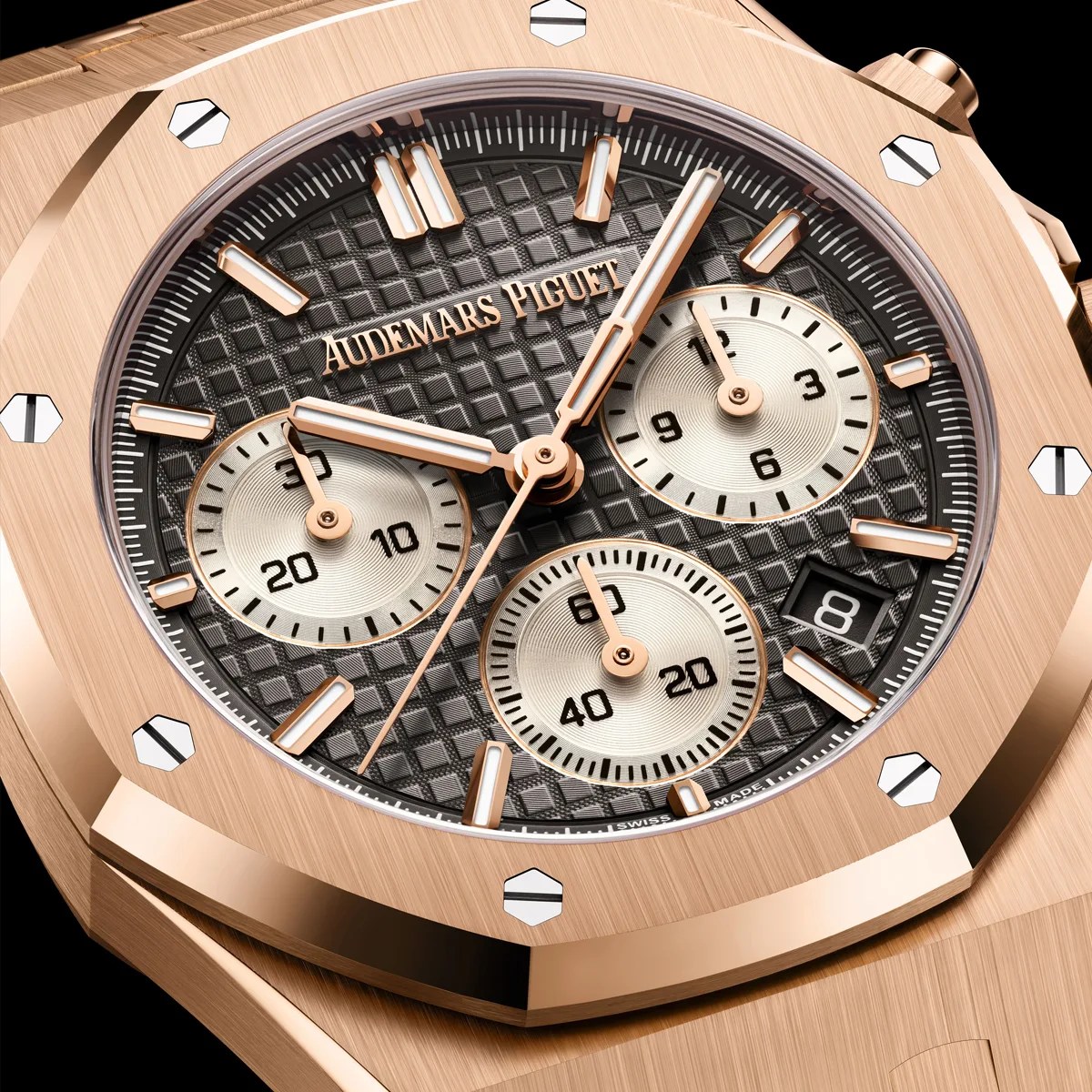 Close-up of a rose gold Audemars Piguet watch with a black textured dial, three subdials, and a date window.