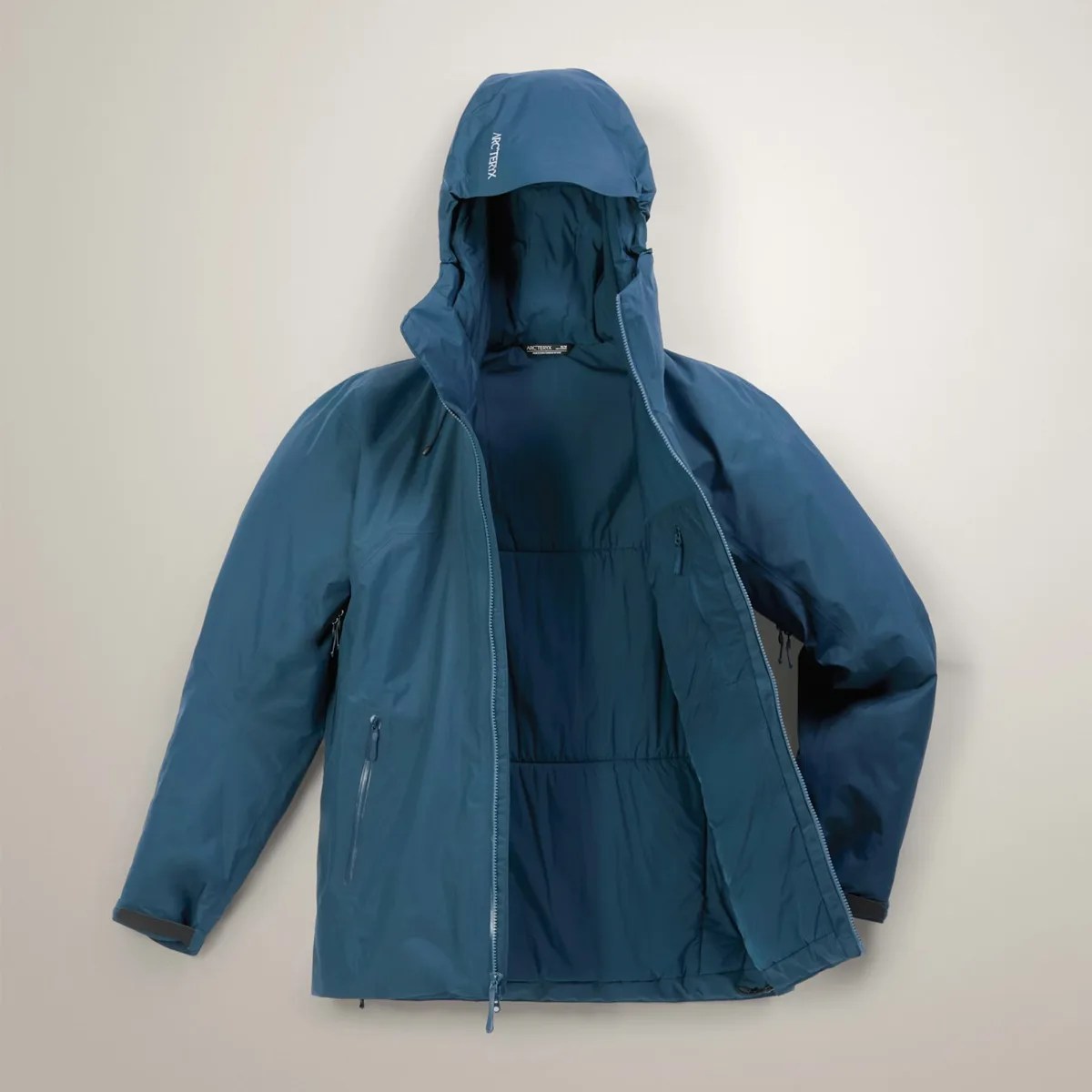 Blue Arc'teryx hooded jacket with front zipper partially open, showing interior lining.