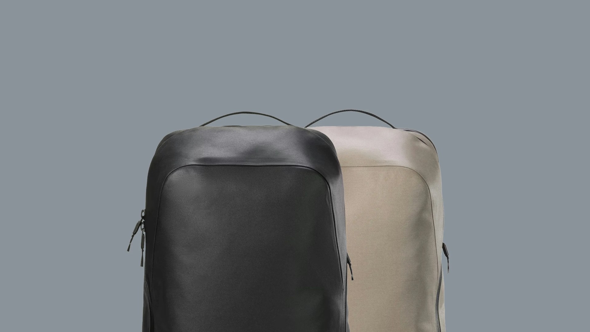 Two minimalist backpacks, one black and one beige, with top handles against a gray background.