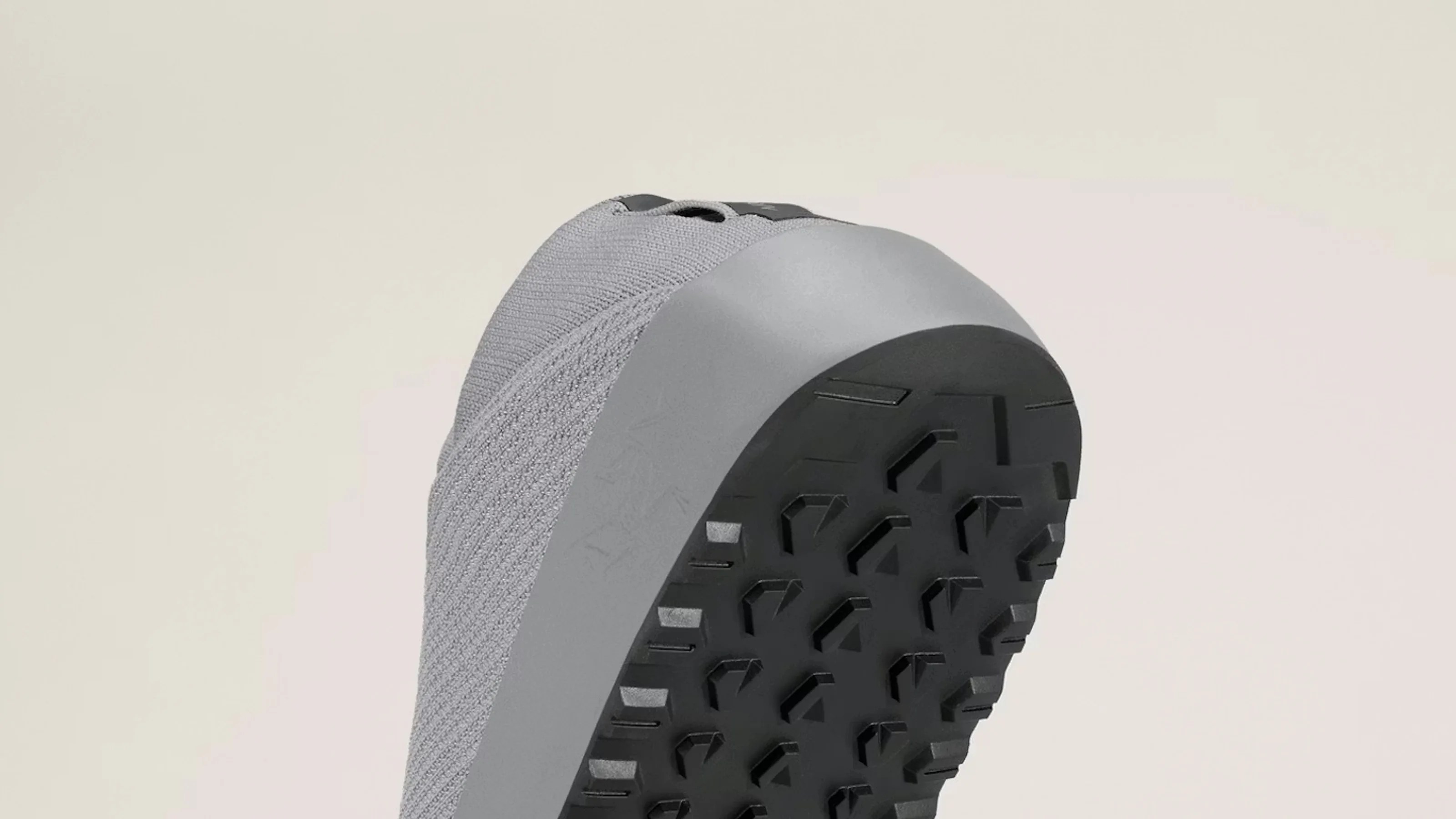 Gray knit sneaker with a thick gray midsole and black textured rubber outsole shown from the bottom angle.