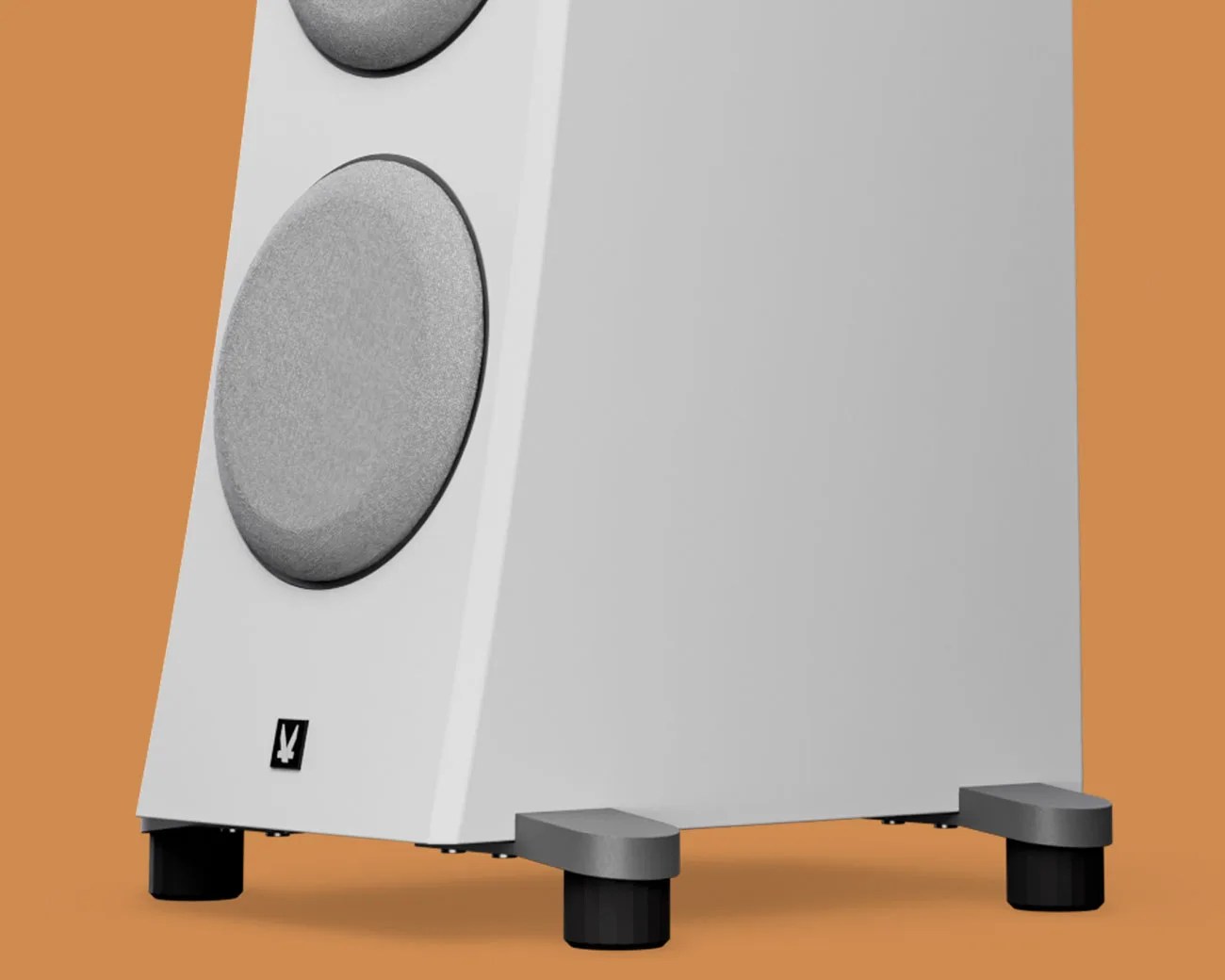 White floor-standing speaker with gray circular drivers and black feet on an orange background.