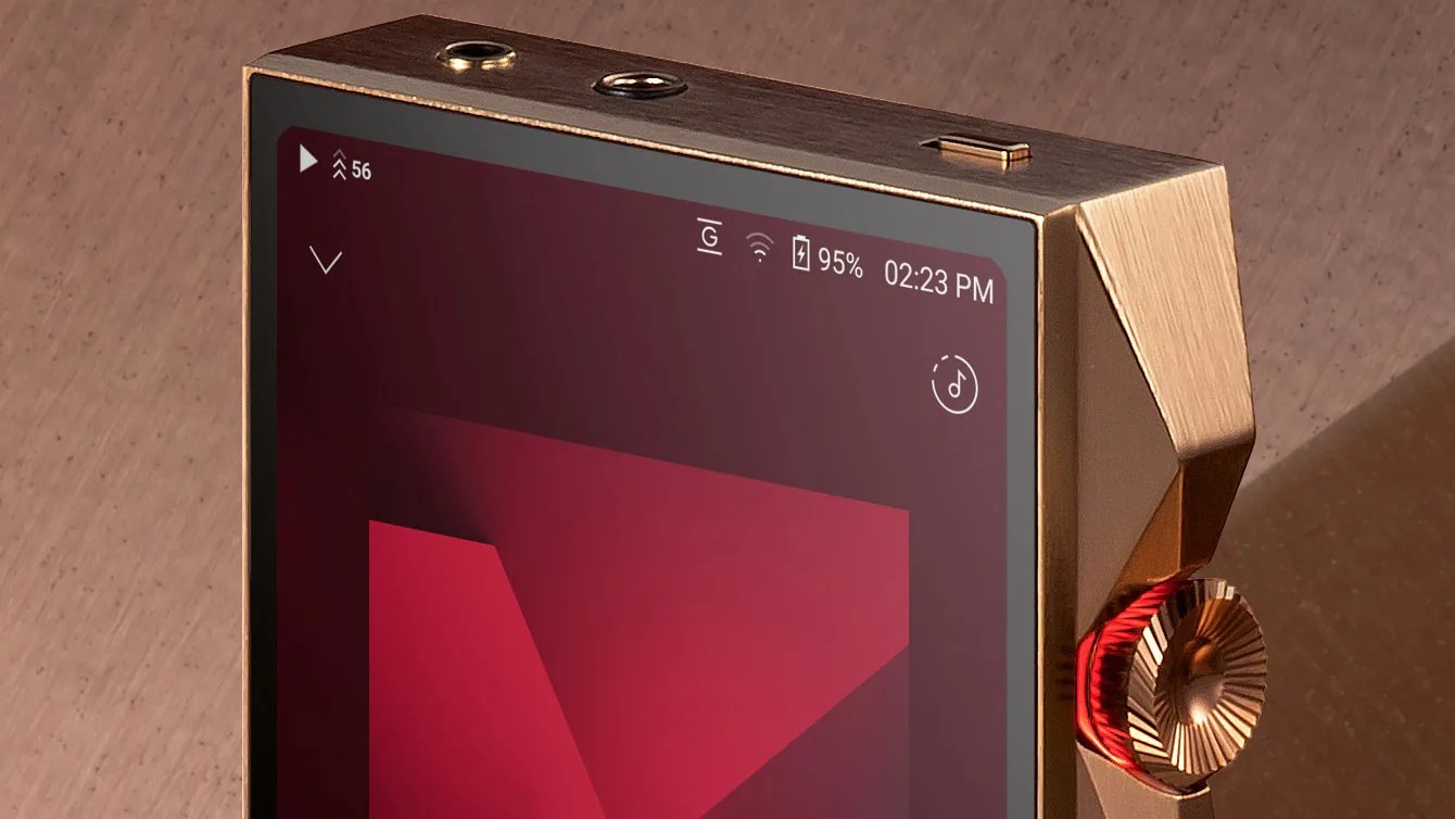 Close-up of a gold-colored digital music player with a red volume knob and a screen showing battery at 95% and time 02:23 PM.