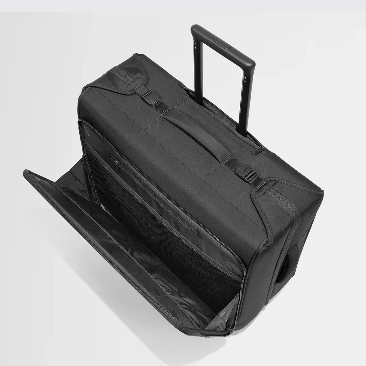 Black wheeled duffel bag with extended handle and open front zippered compartment showing mesh pocket.