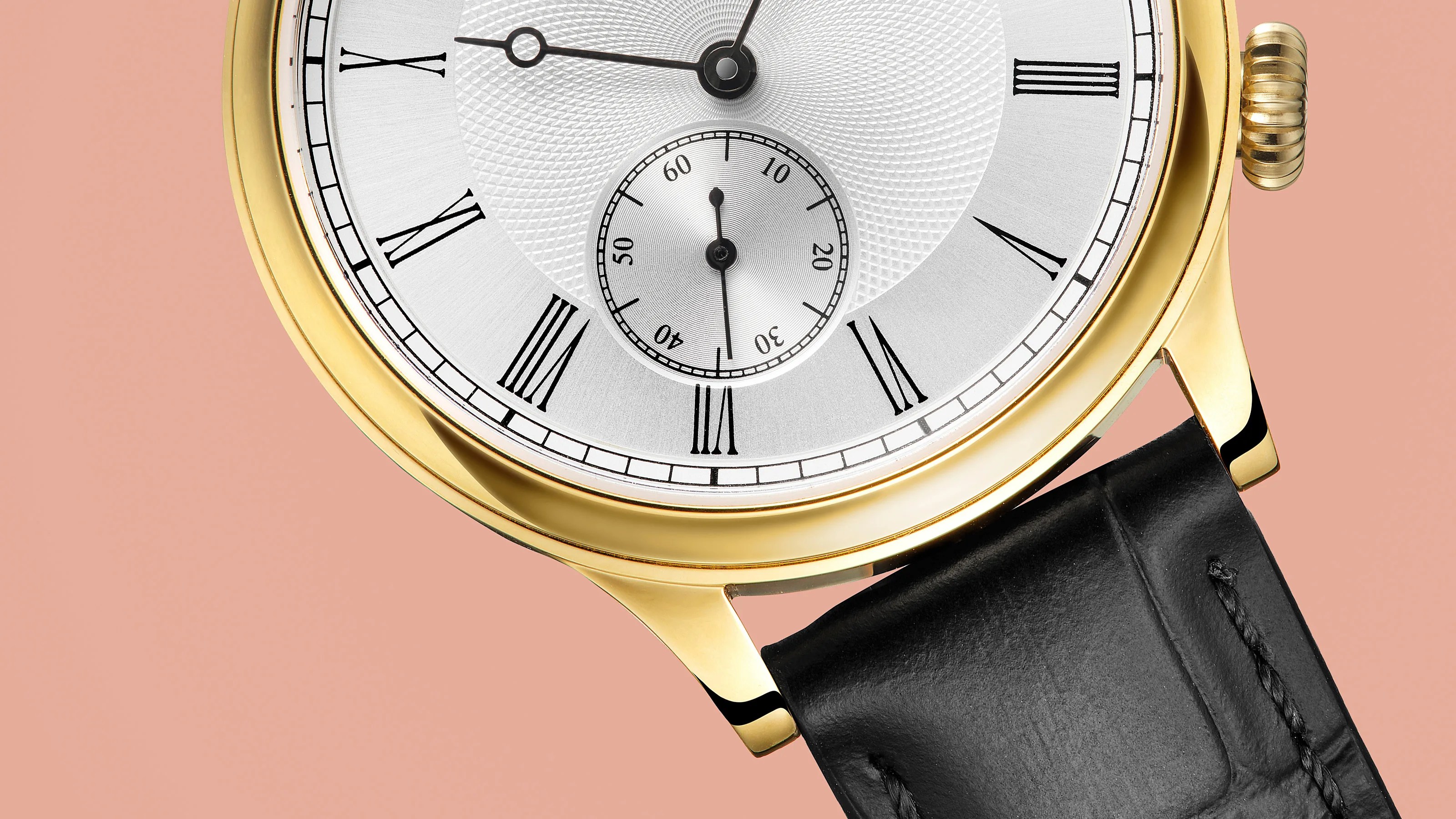 Close-up of a gold watch with a white dial, black Roman numerals, and a black leather strap on a peach background.