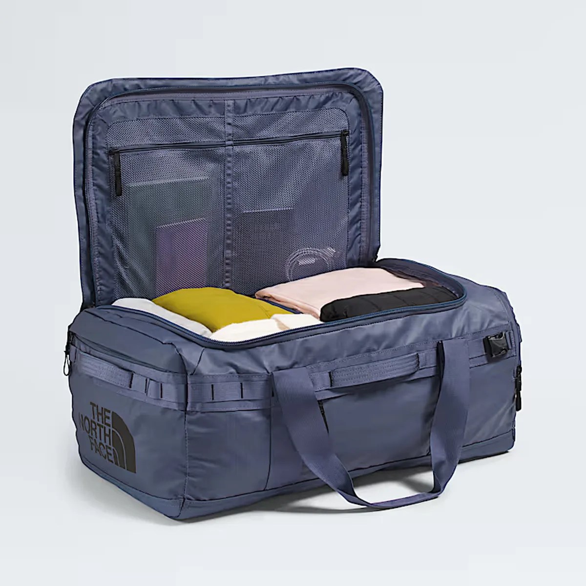 Blue rectangular duffel bag with black "The North Face" logo, open with folded clothes inside.