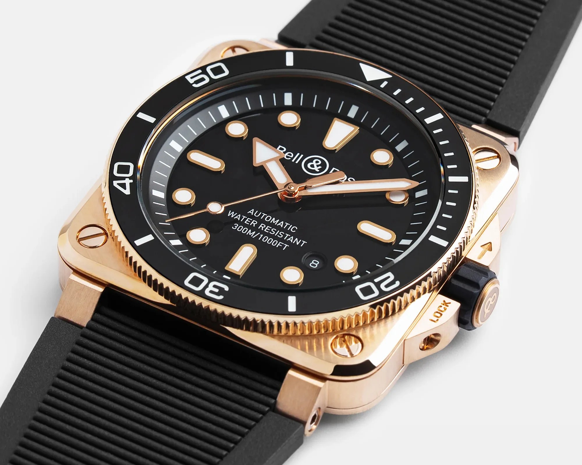 Square rose gold watch with black dial, luminous markers, rotating bezel, and black rubber strap.