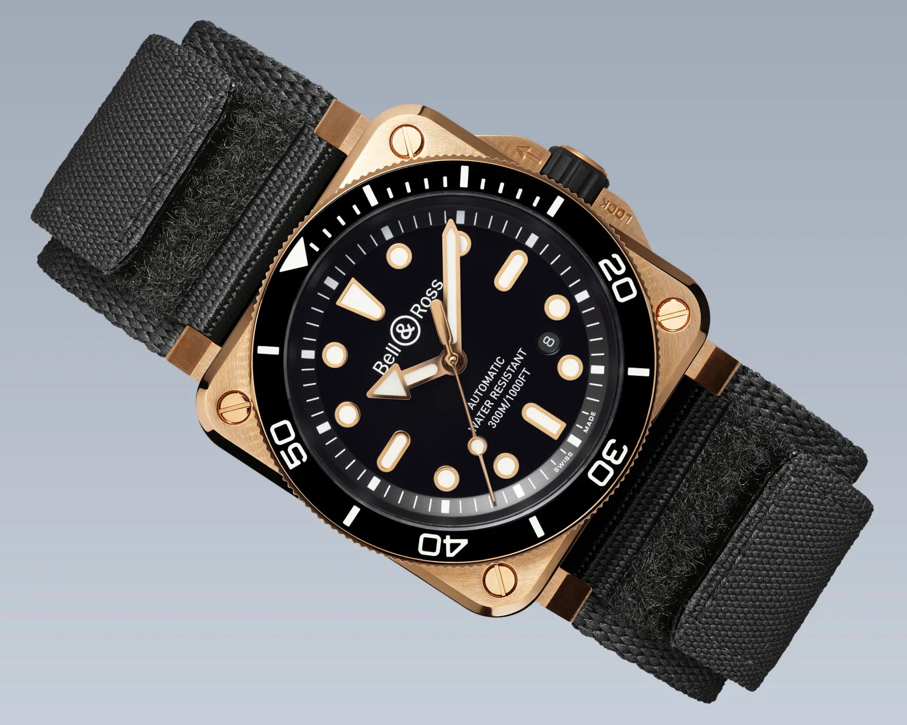 Square bronze Bell & Ross dive watch with black dial, luminous markers, rotating bezel, and black fabric strap.