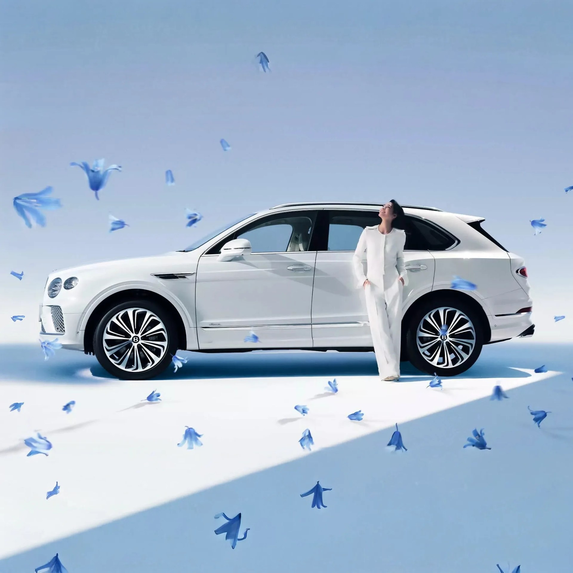 White luxury SUV with black-tinted windows and large alloy wheels, surrounded by floating blue flowers.