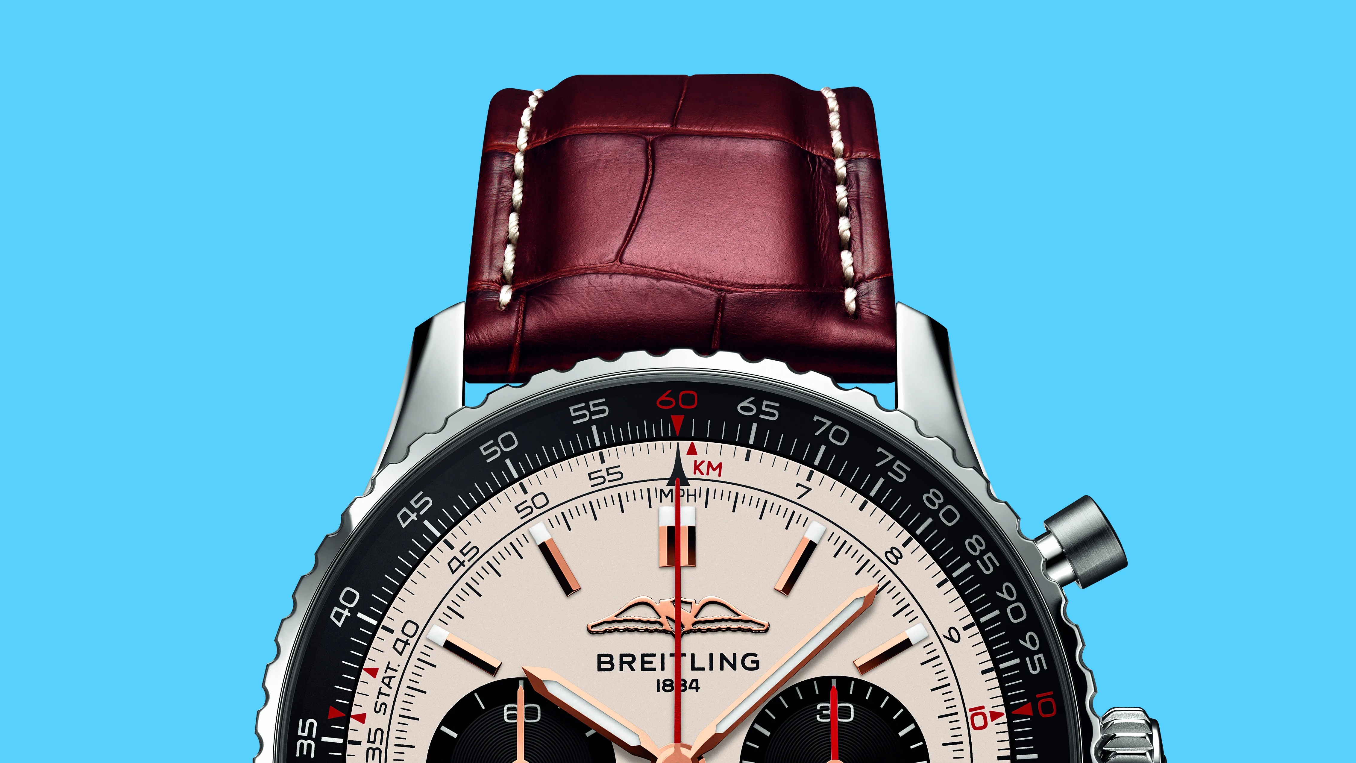 Close-up of a Breitling watch face with rose gold hands, black subdials, and a brown leather strap against a blue background.