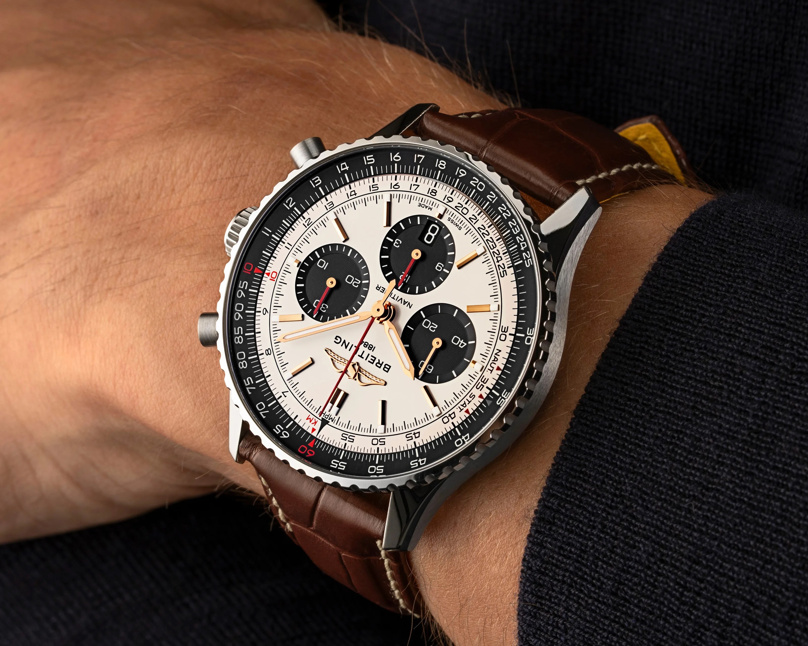 Breitling Navitimer wristwatch with white dial, black subdials, and brown leather strap on a wrist.