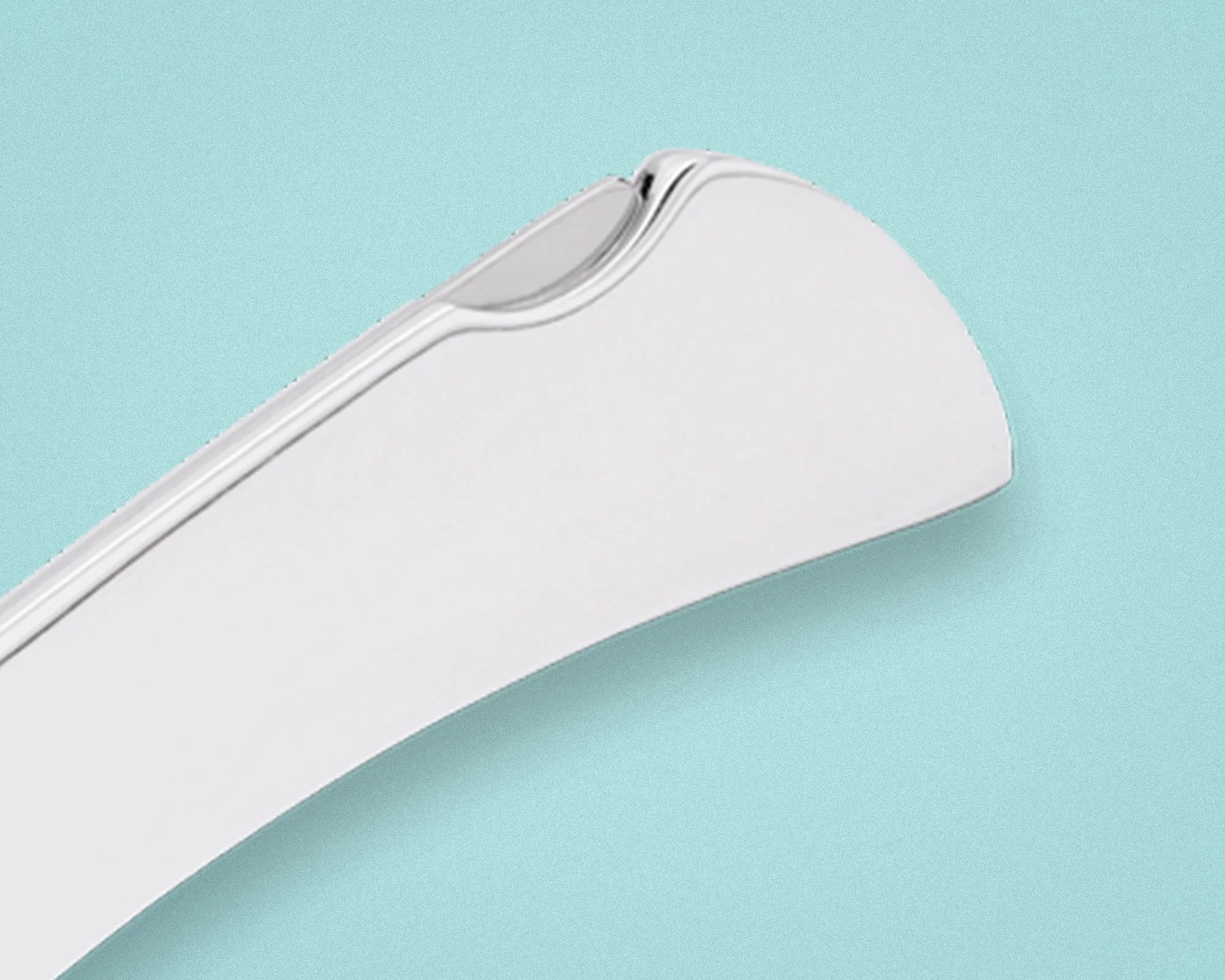 Close-up of a white curved plastic object with a transparent clip on a light blue background.